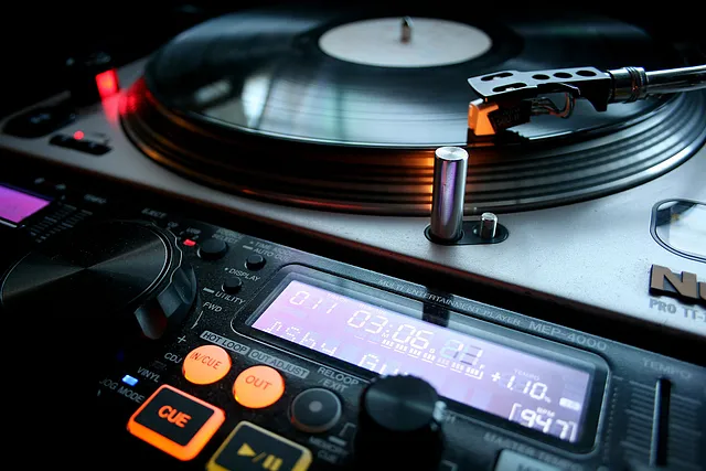 The image evokes a sense of musical energy and the creative process of a DJ. The focus on the turntable and the spinning record suggests the act of mixing music and controlling the flow of sound.